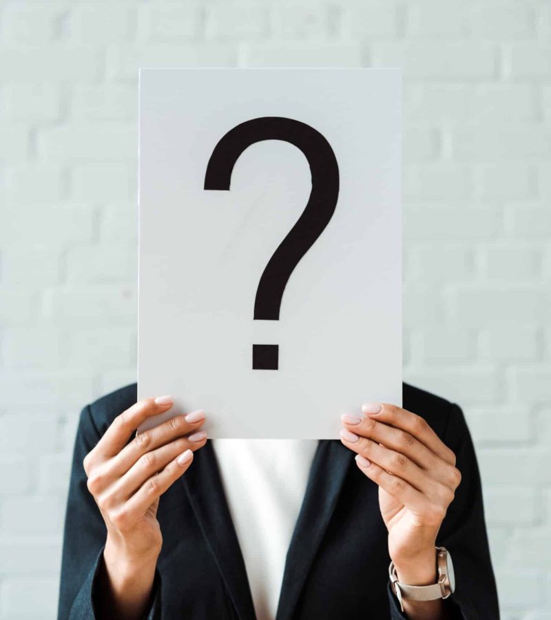 cropped view of woman holding placard with question mark near brick wall